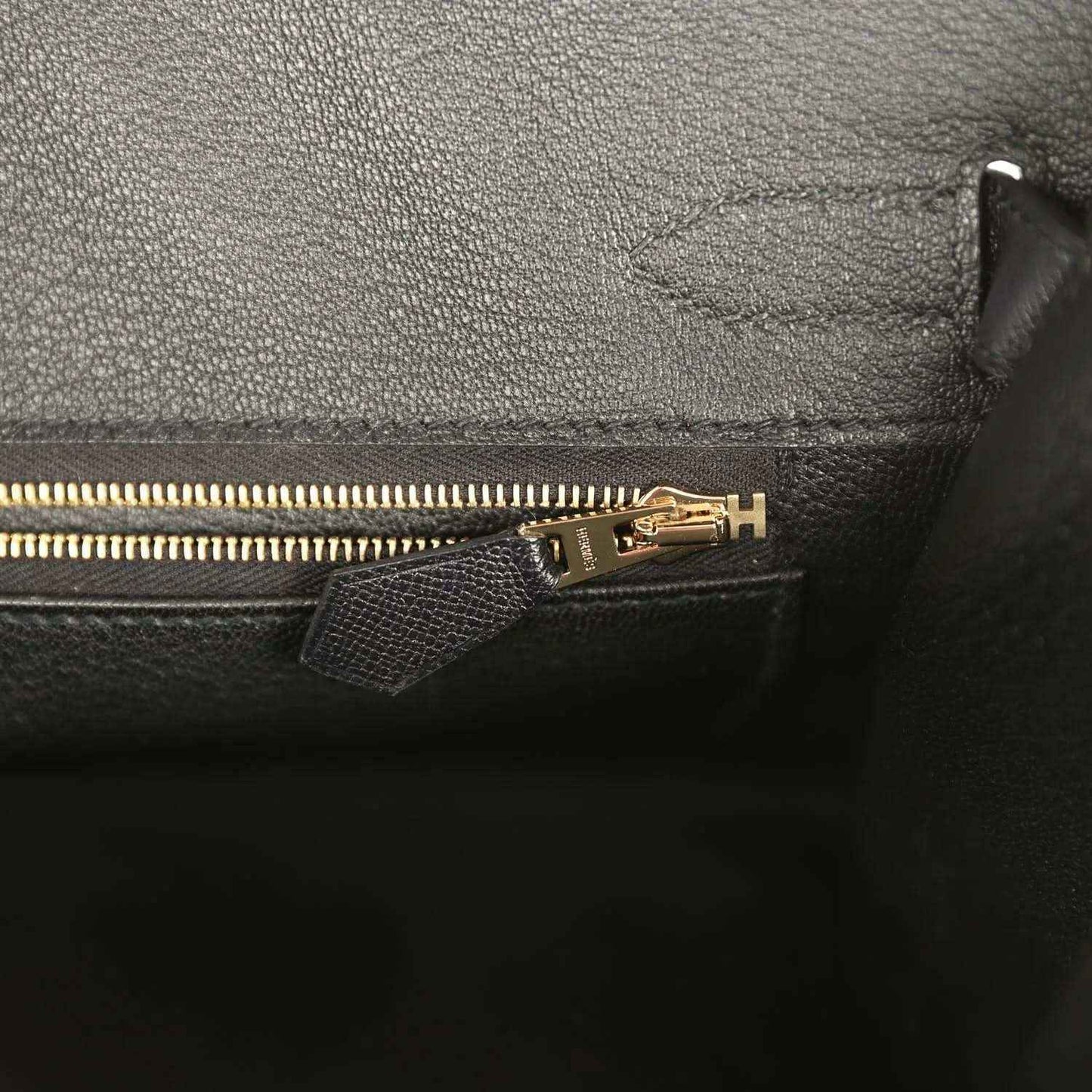 Birkin handbag close-up of gold zipper pull and interior pocket edge