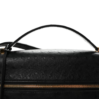 Black ostrich leather handbag with top handle and front zip, showing textured leather detail