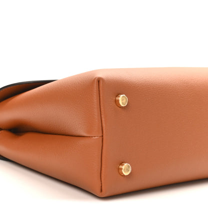 Tan leather handbag corner close-up with two gold snap buttons and clean side seam