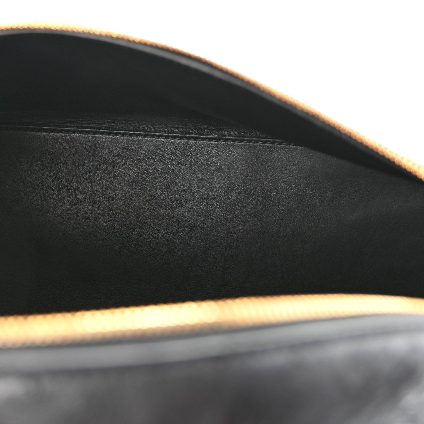 Close-up of black ostrich leather interior edge with gold-tone trim and smooth lining