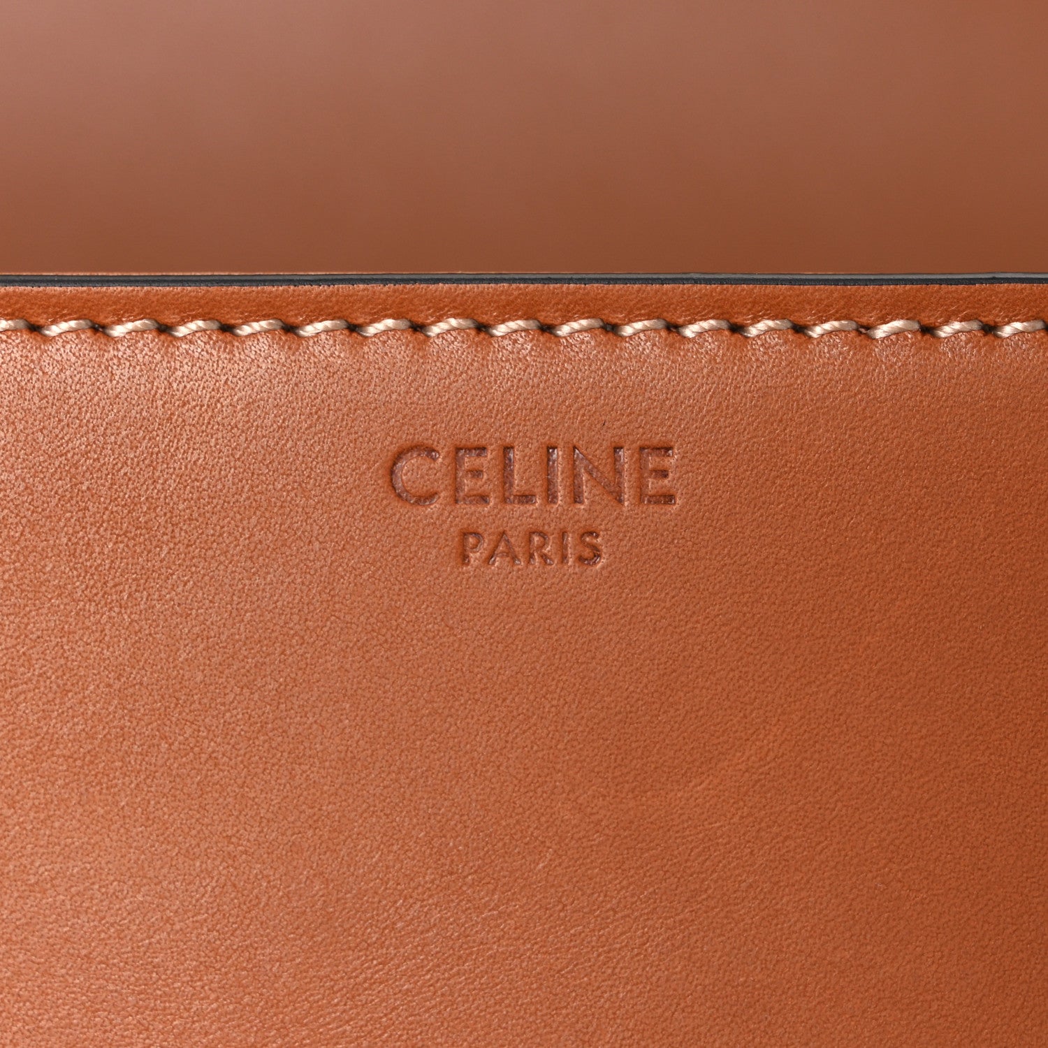 Celine embossed mark on tan leather panel with decorative stitched trim.