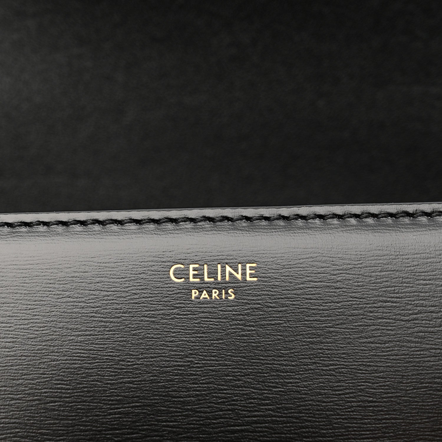 Black leather bag lining with 'CELINE PARIS' embossed text and stitched edge.