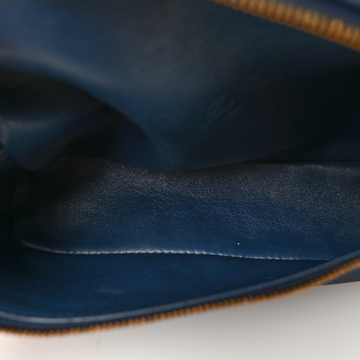 Navy grained calfskin pouch with gold zipper edge and close-up stitching