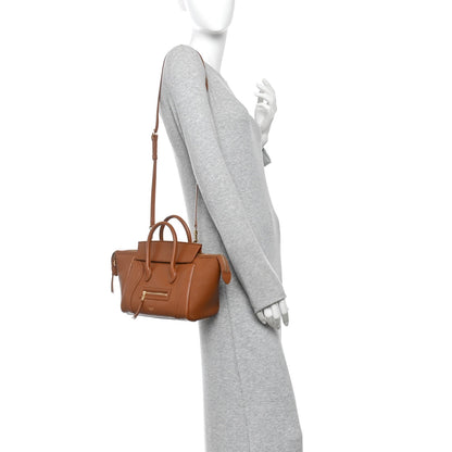 Tan leather mini tote with long crossbody strap, shown on a model