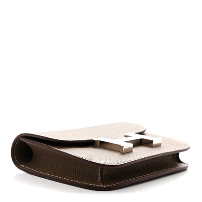Taupe slim wallet shown open with H clasp detail and white stitching