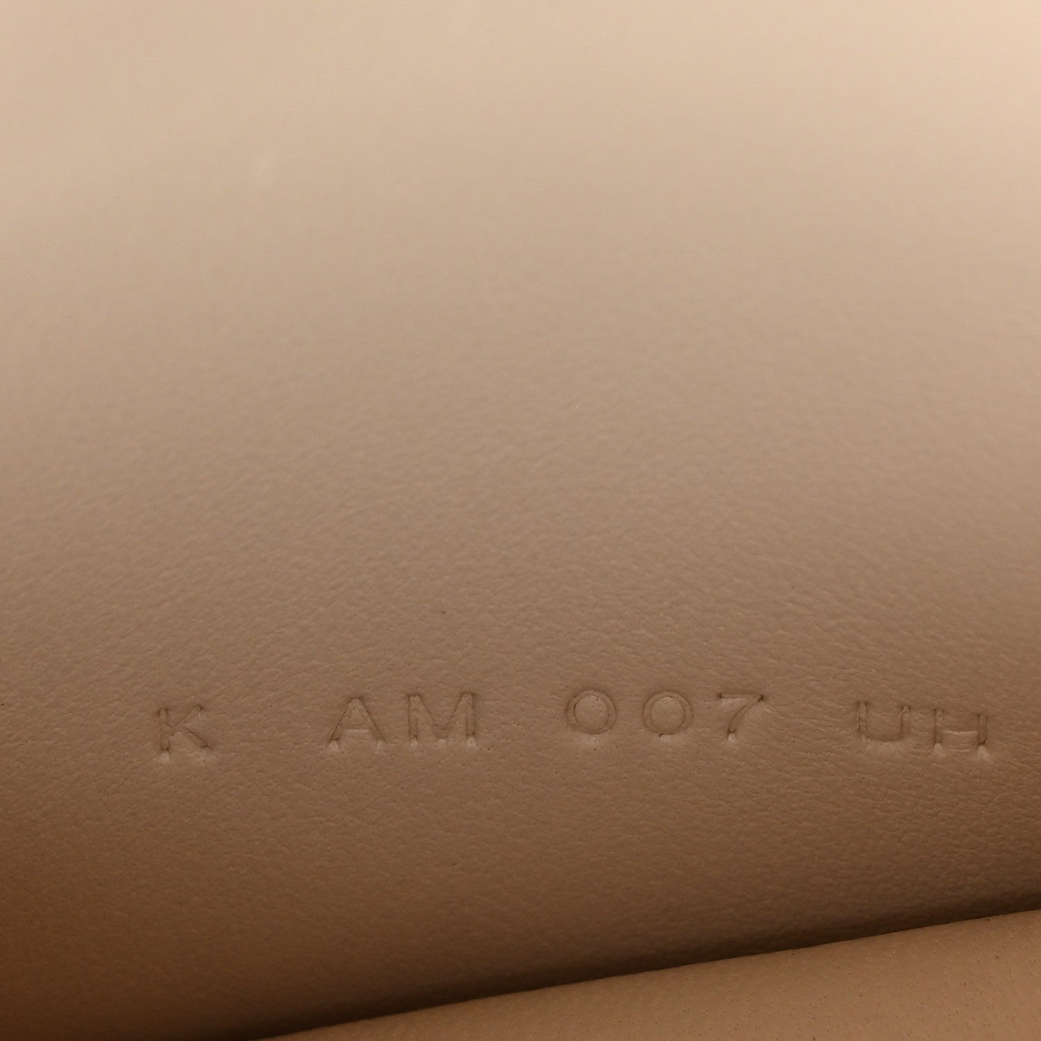 Stamped code on light cream leather, faint marks visible