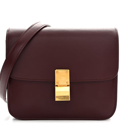 Burgundy leather box flap bag with gold-tone front clasp and top handle strap.