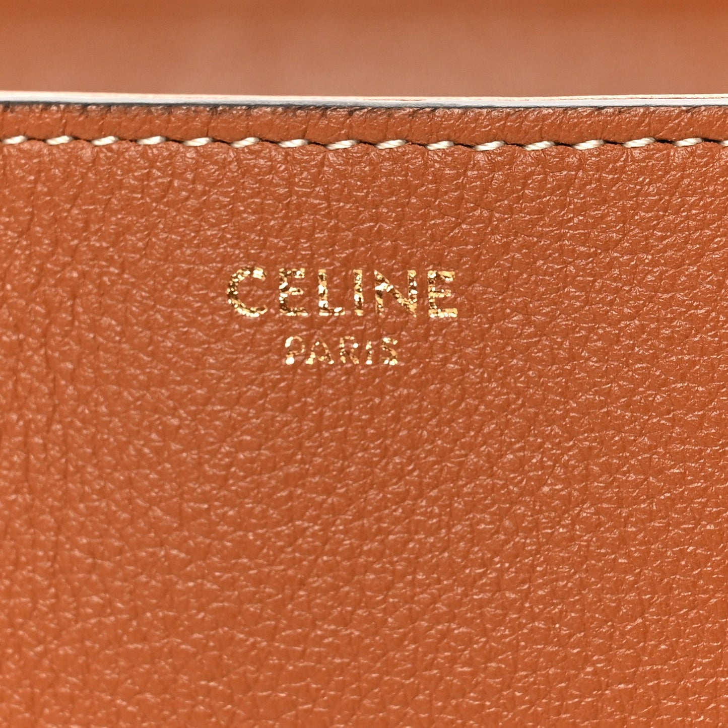 Tan grained calfskin close-up with embossed CELINE branding and stitched edge