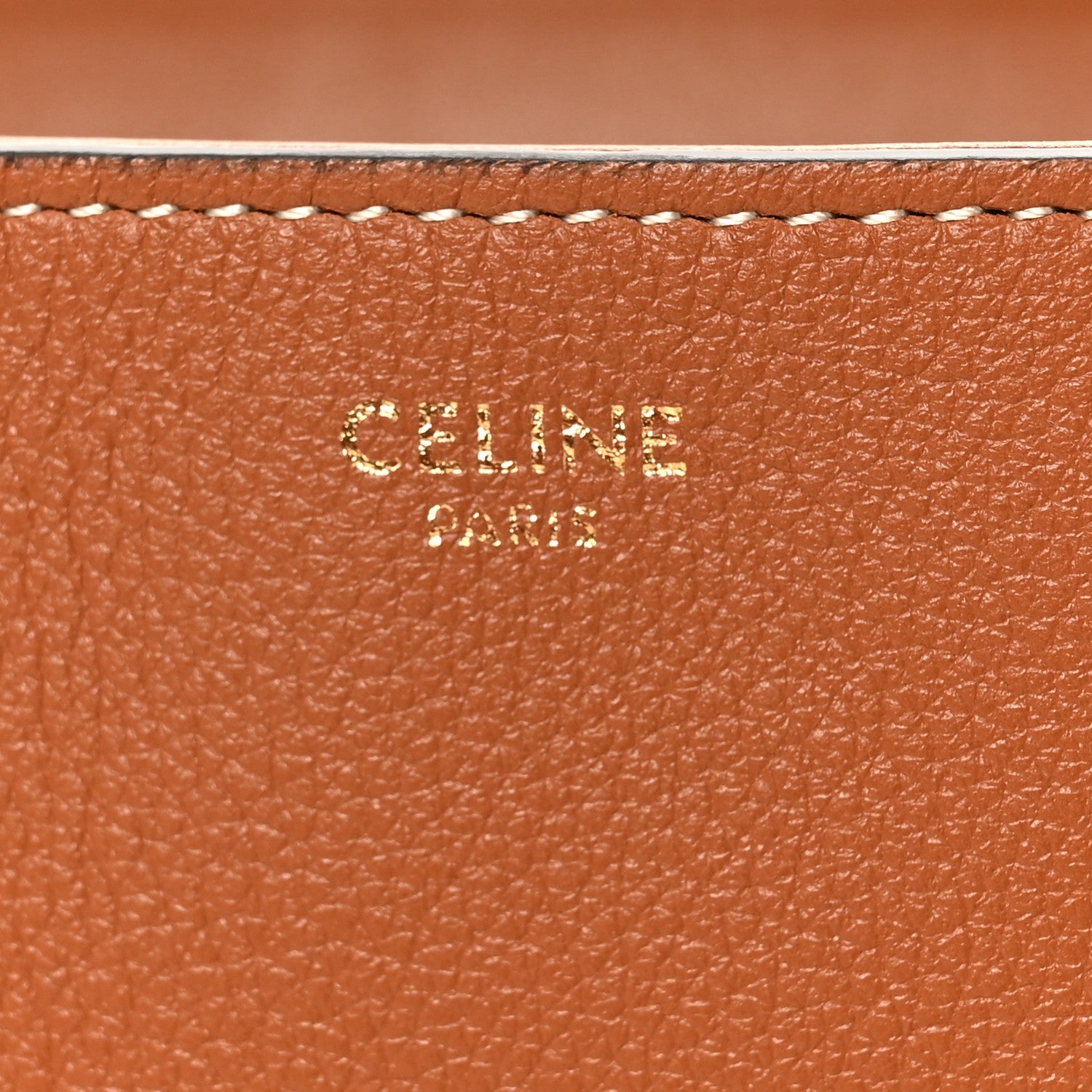 Tan grained calfskin close-up with embossed CELINE branding and stitched edge