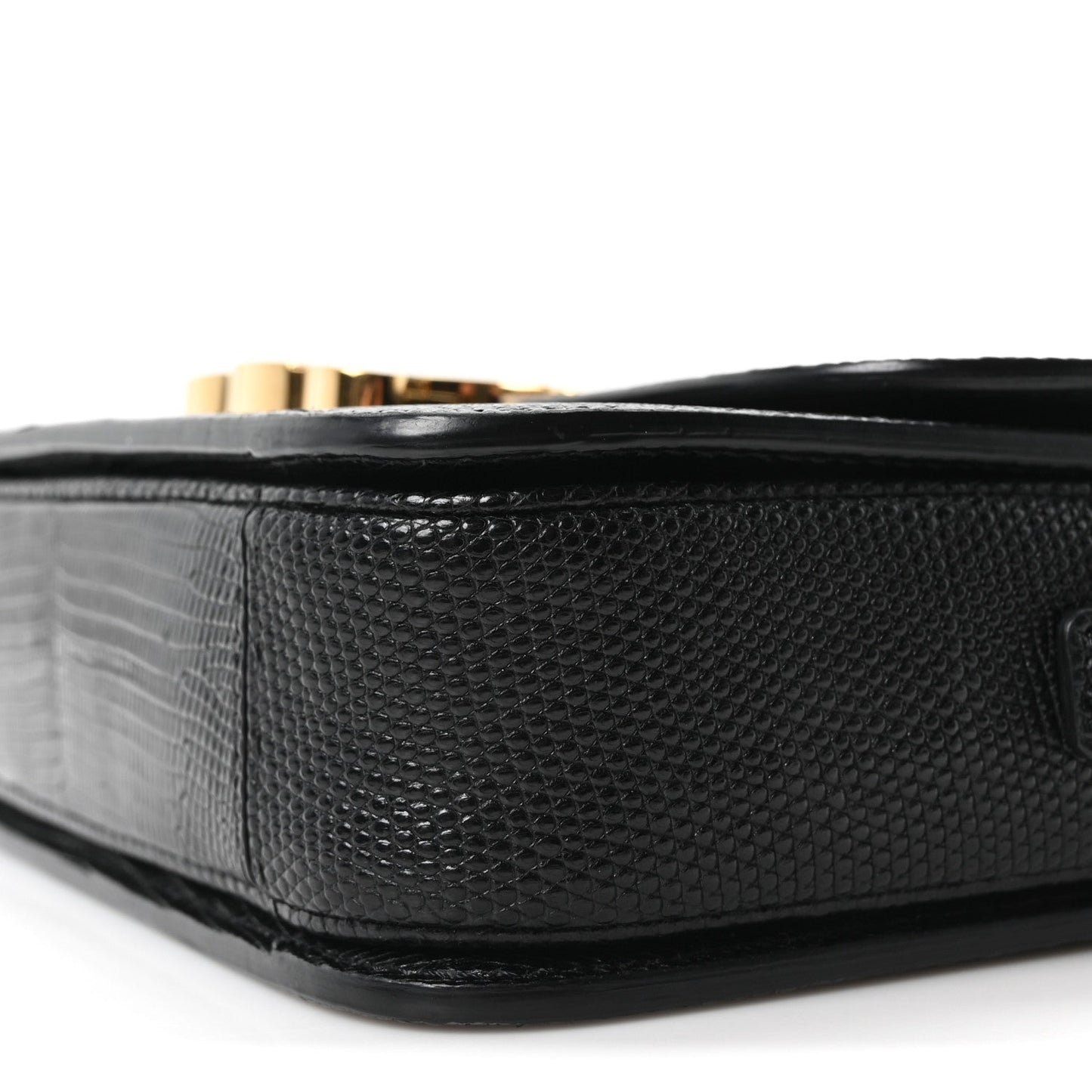 Black lizard-embossed flap bag side with gold hardware peeking