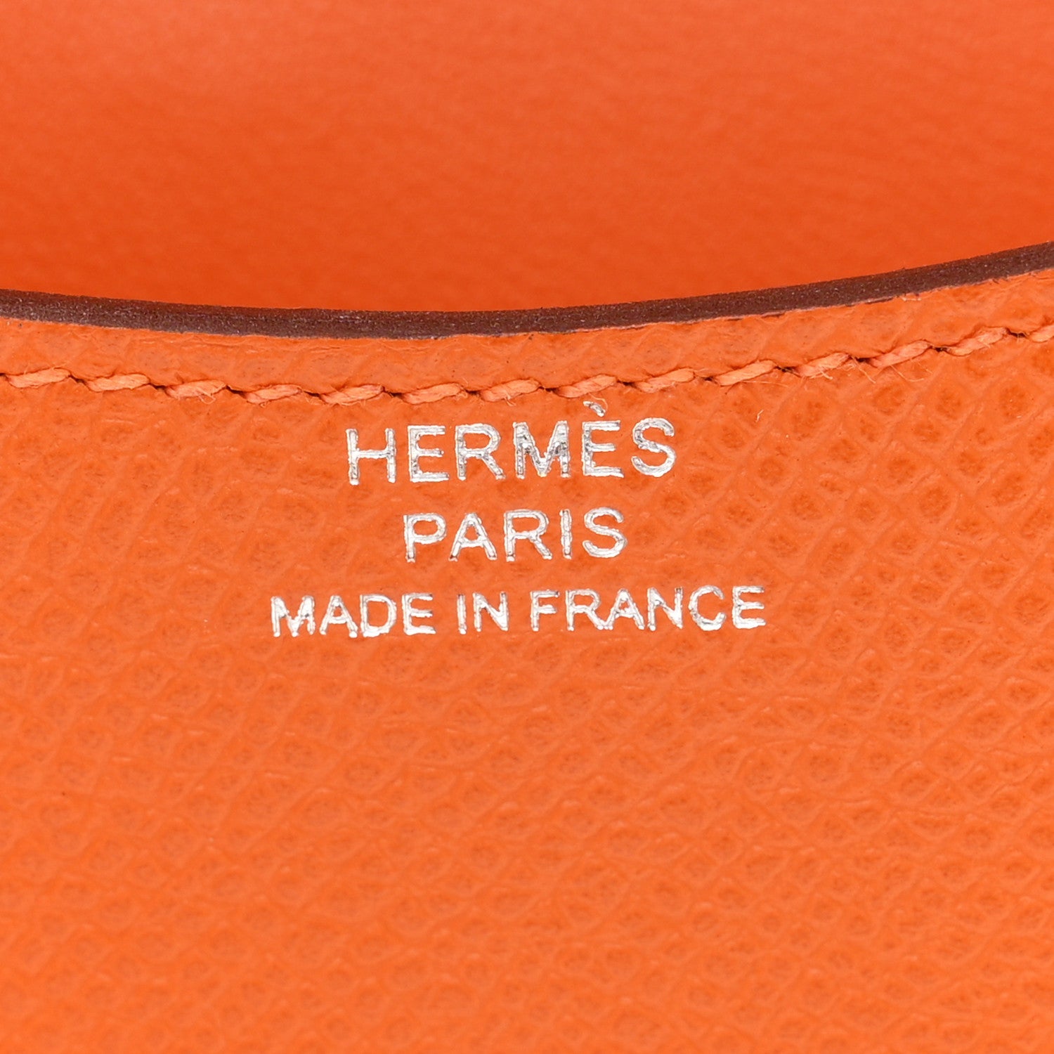 Hermes Paris Made in France stamp on orange leather slim wallet.