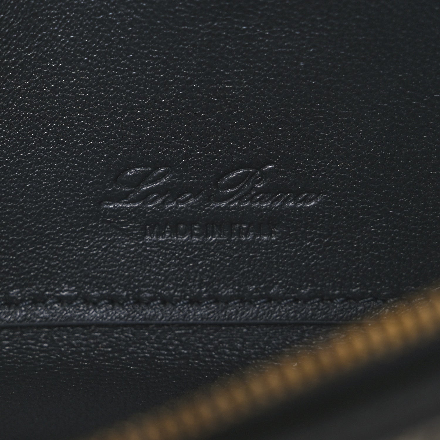 Embossed Loro Piana logo on dark navy leather flap with visible stitching