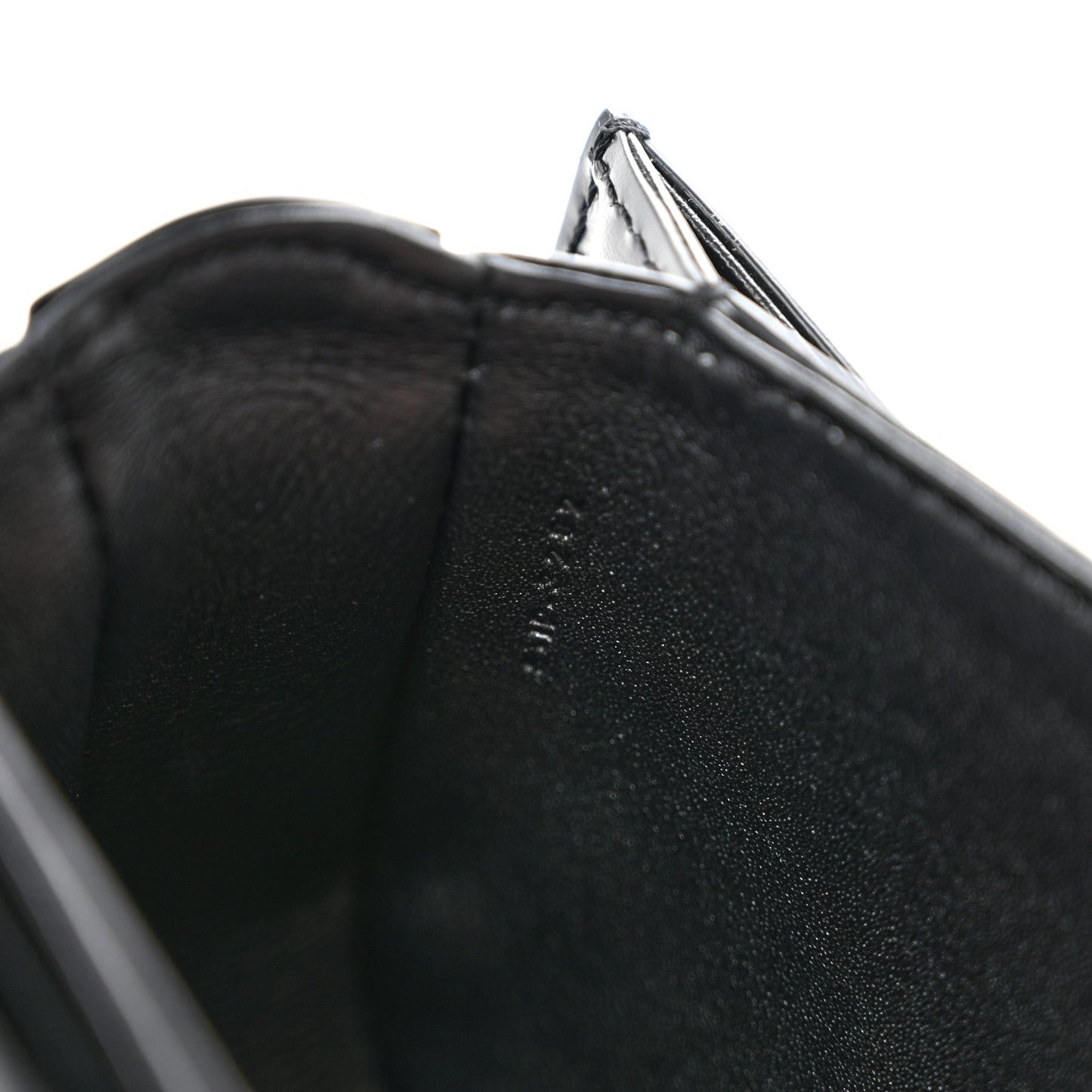 Black shiny mini crossbody bag, close-up of leather edge and open top lining