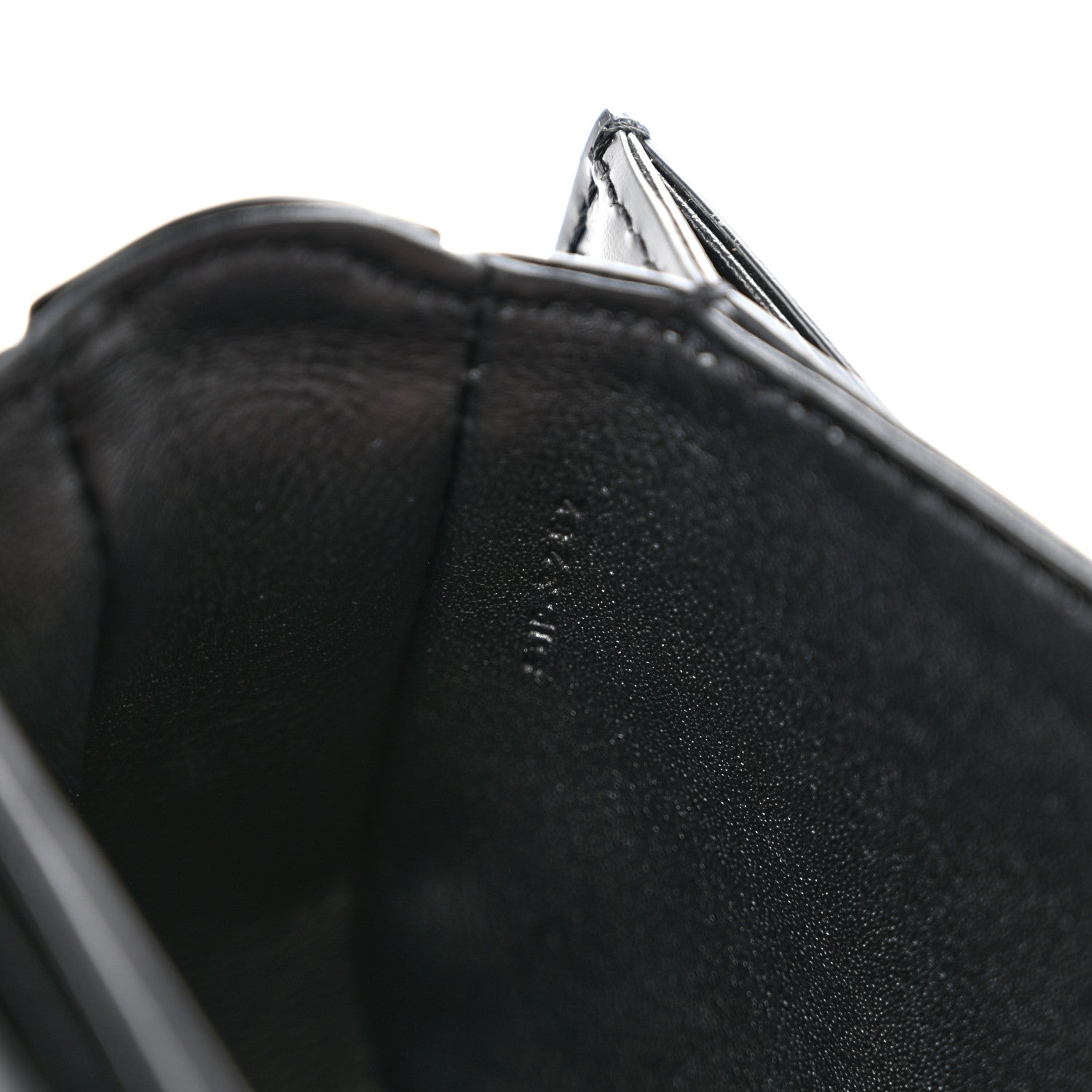 Black shiny mini crossbody bag, close-up of leather edge and open top lining