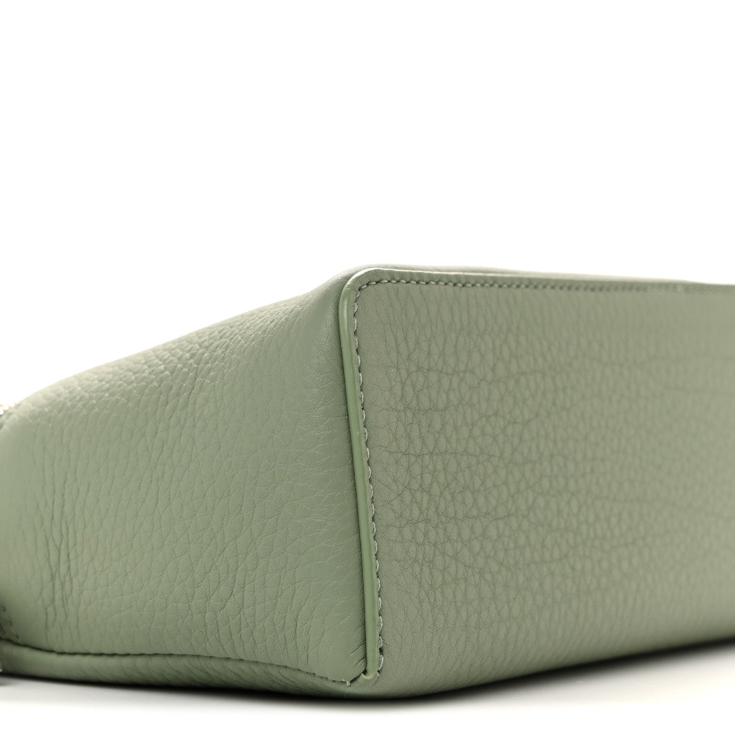 Sage green grained calfskin pouch corner with stitched seam, close-up