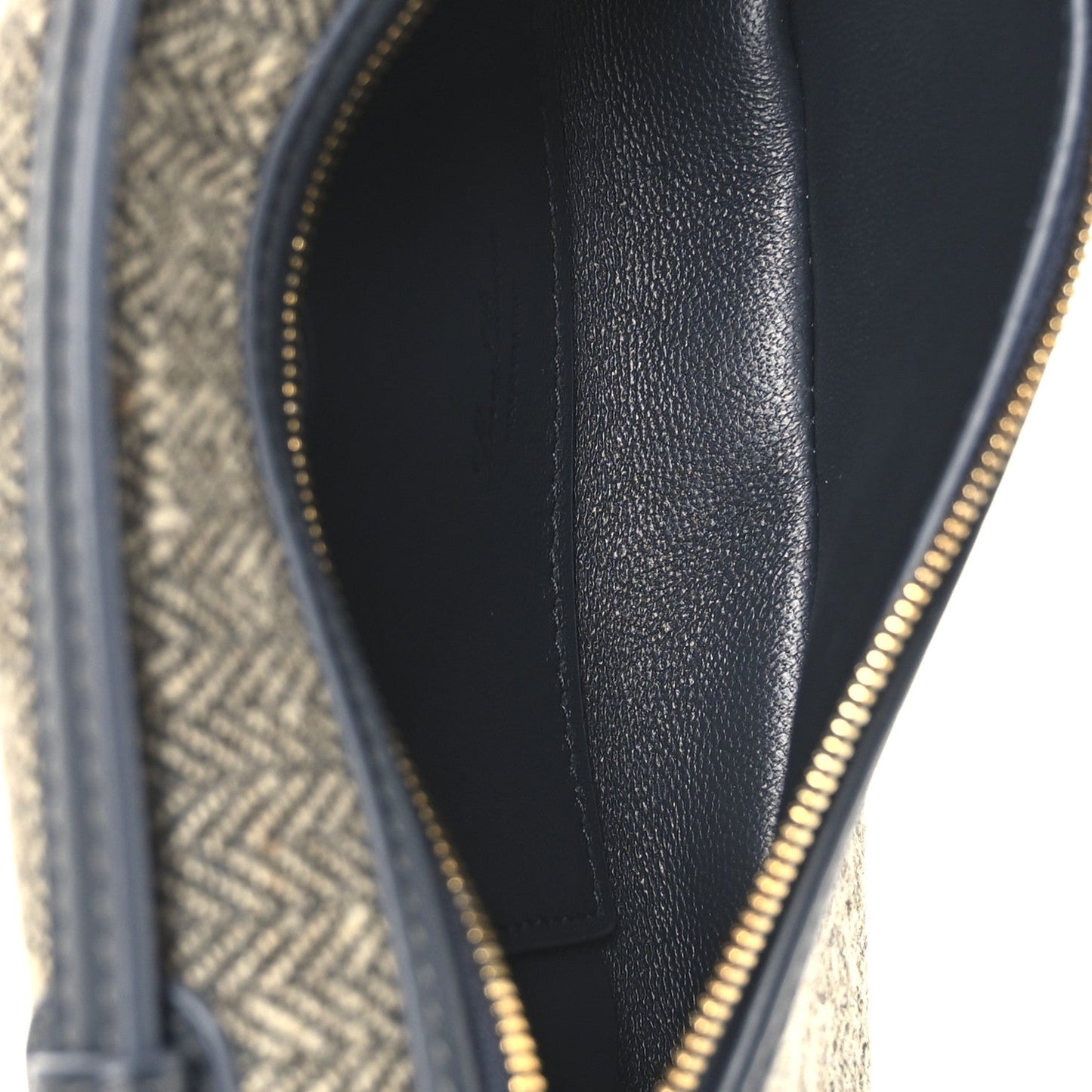 Close-up of navy leather lining and gold zipper track on a mini herringbone pouch