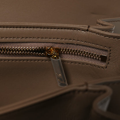 Shiny brown leather bag close-up of gold-tone zipper and clear zip pull