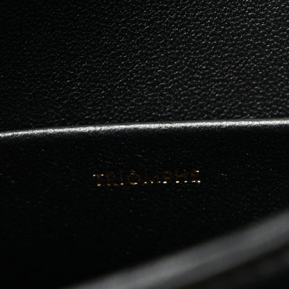 Close-up of black leather with faint embossed logo on bag panel.