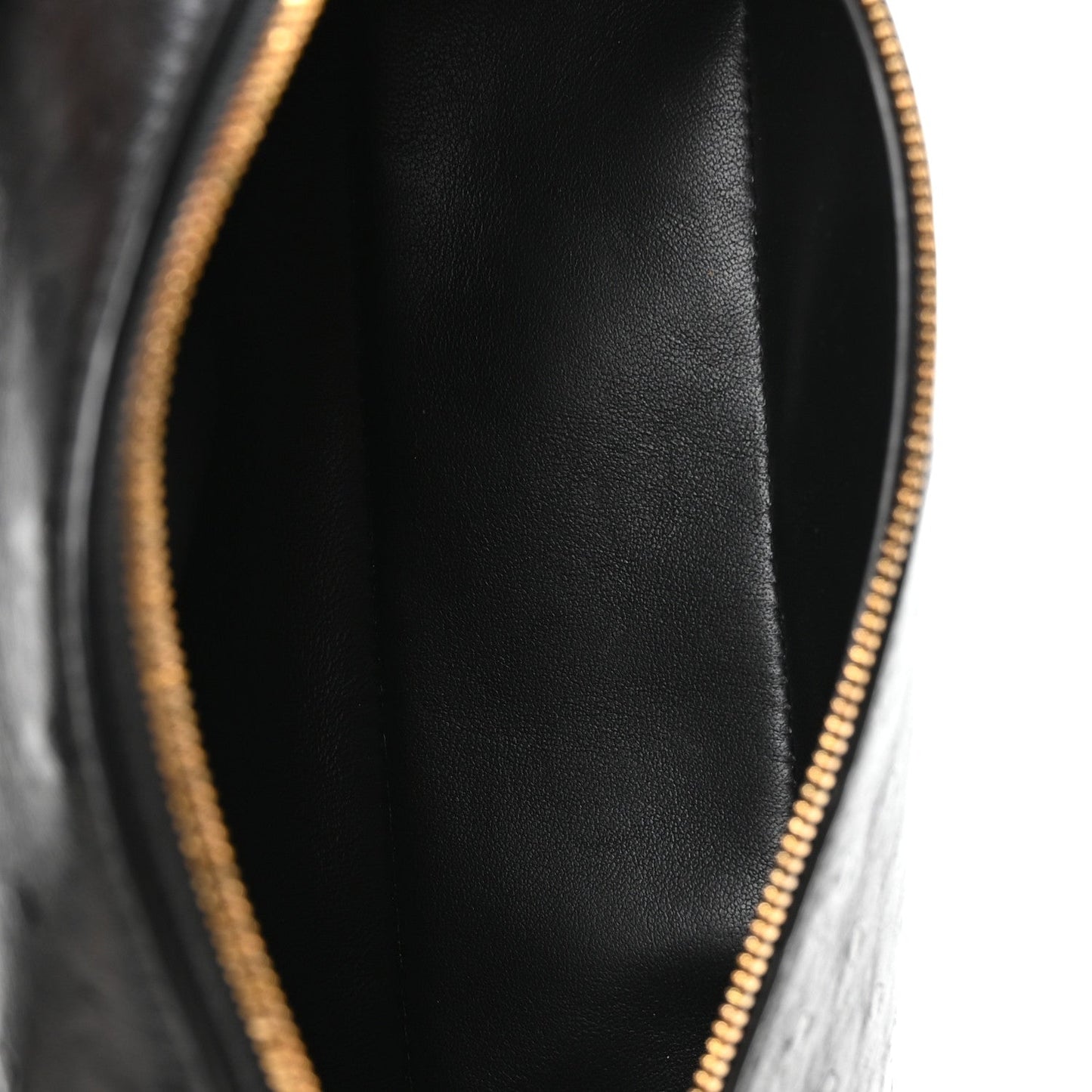 Close-up of black interior lining and gold-tone zipper at pouch opening