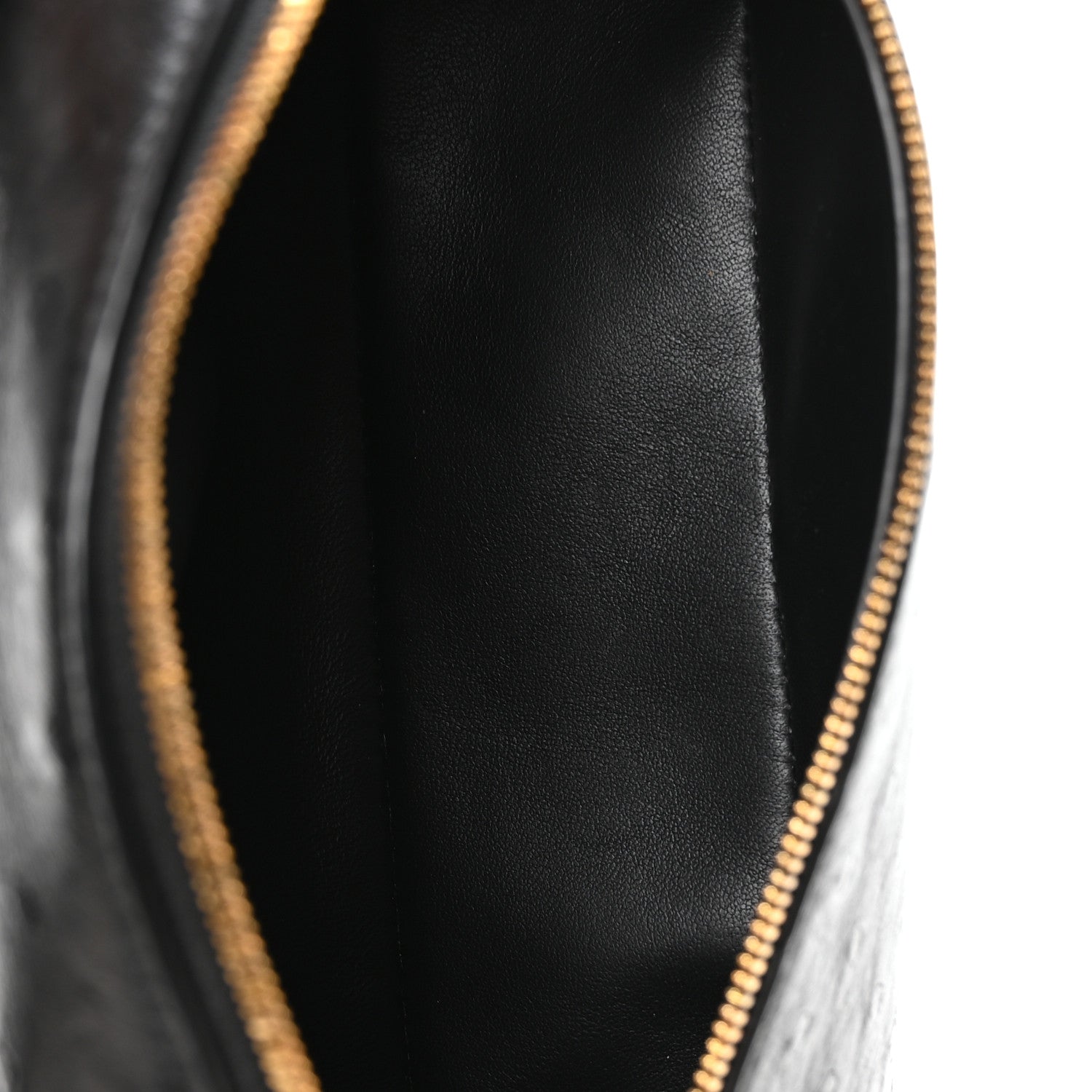 Close-up of black interior lining and gold-tone zipper at pouch opening