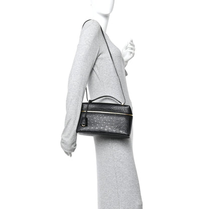 Black ostrich leather crossbody mini bag with shoulder strap and front zip closure on person