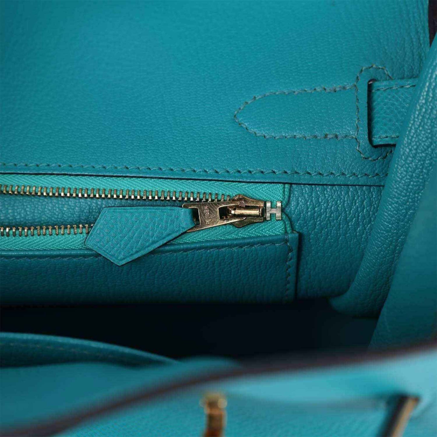 Elegant turquoise leather handbag interior with gold zipper and refined stitching