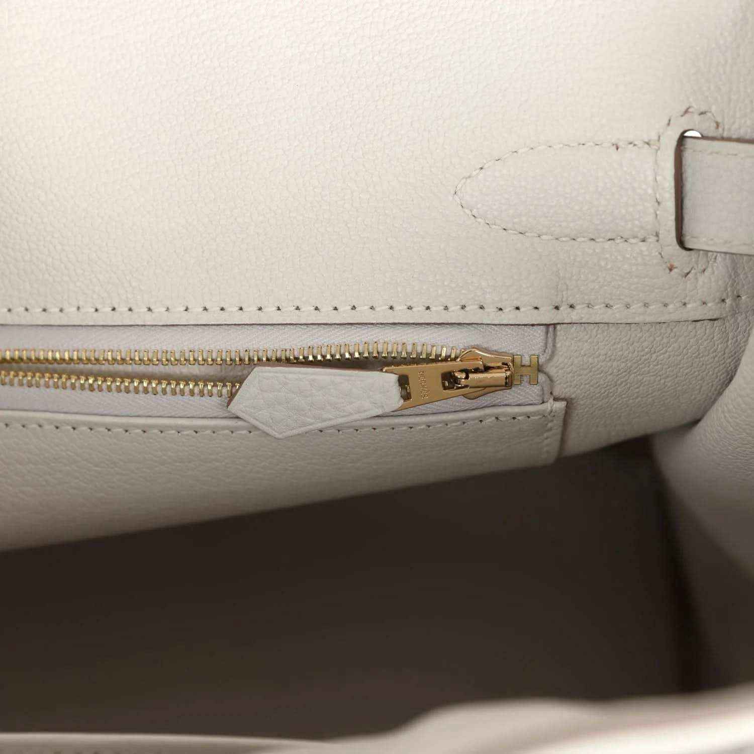 Elegant white leather handbag interior with gold zipper, sophisticated and timeless.