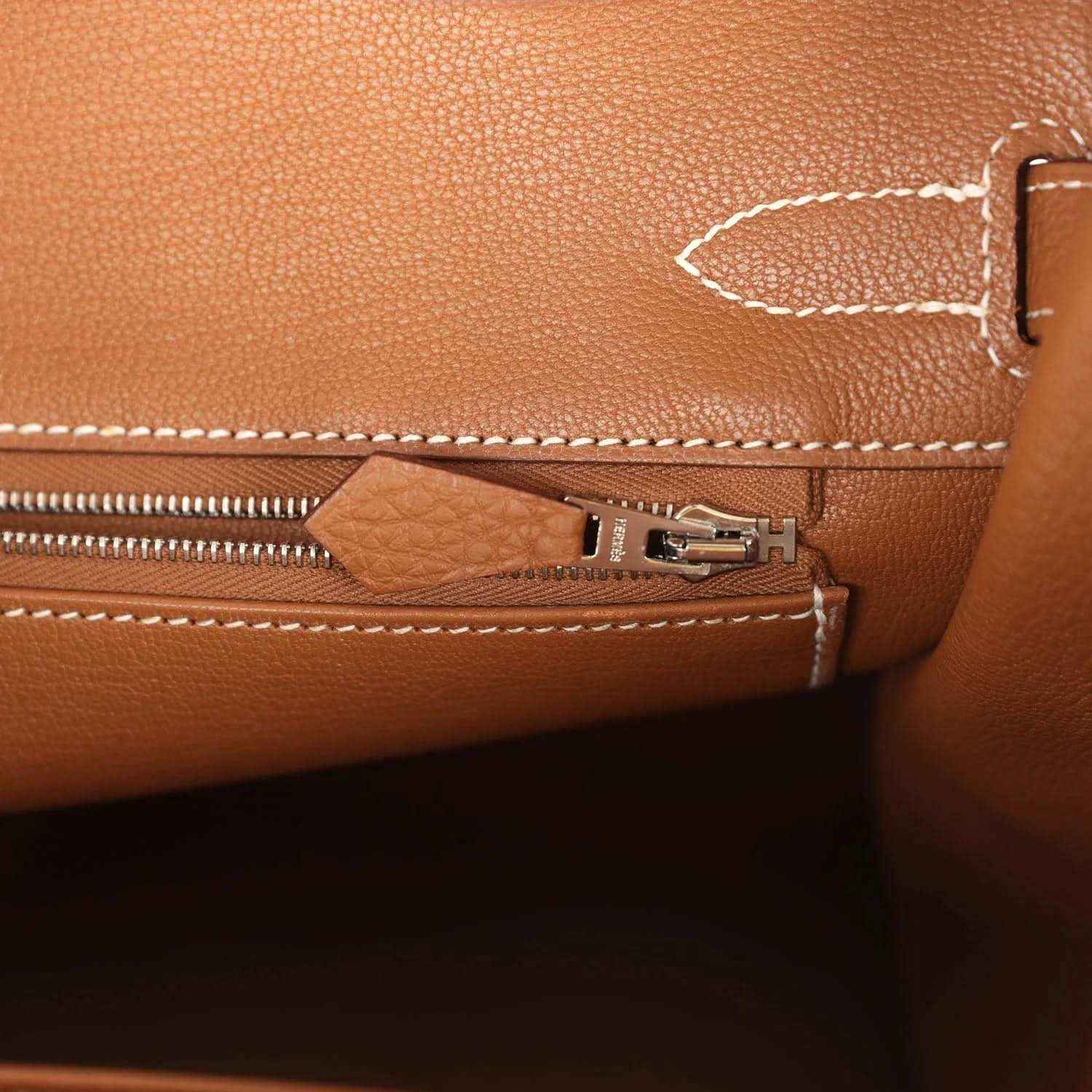 Elegant tan leather handbag interior with refined white stitching and a silver zipper