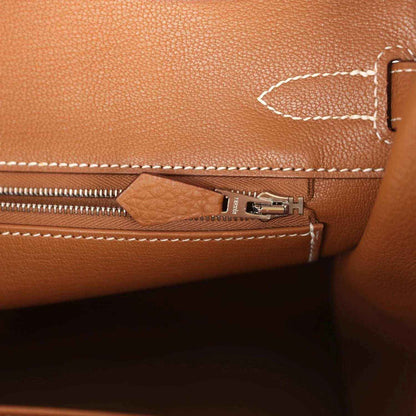 Elegant tan leather handbag interior with refined white stitching and a silver zipper