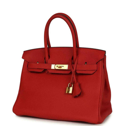 Elegant red leather handbag with gold hardware and top handles, timeless and sophisticated.