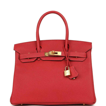 Elegant red leather handbag with gold hardware and a timeless, sophisticated design.