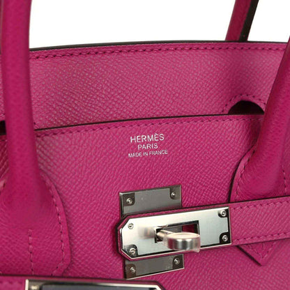 Timeless and sophisticated fuchsia leather handbag with elegant silver hardware details.