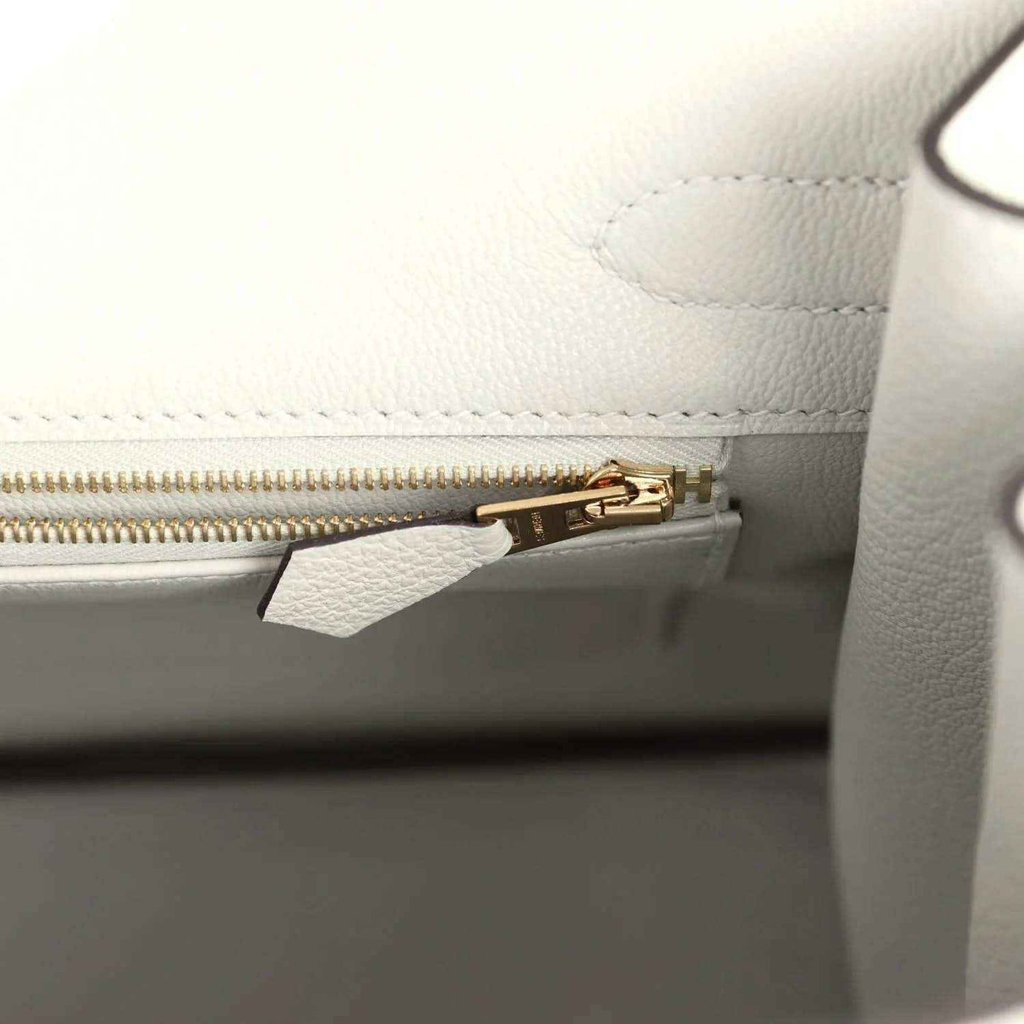 Elegant white leather handbag interior with gold zipper, showcasing timeless sophistication.