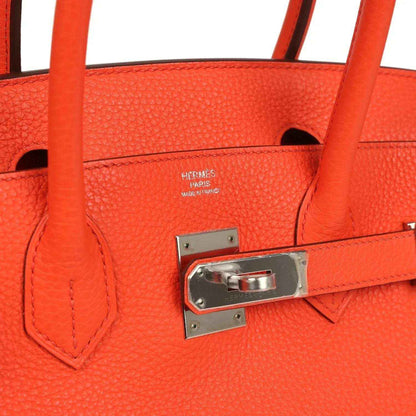 Timeless, elegant orange leather handbag with sophisticated silver hardware details.