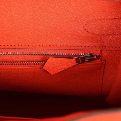 Timeless, elegant orange leather handbag interior with refined zip pocket detail.