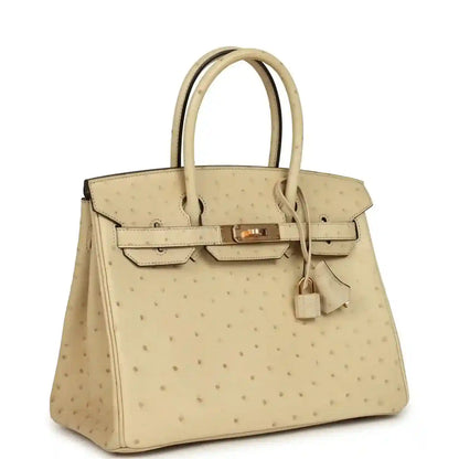 Sophisticated beige leather handbag with textured finish and elegant gold hardware.