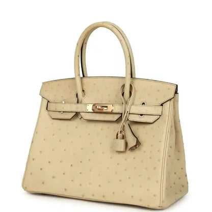 Elegant beige leather handbag with gold hardware, featuring a timeless, sophisticated design.