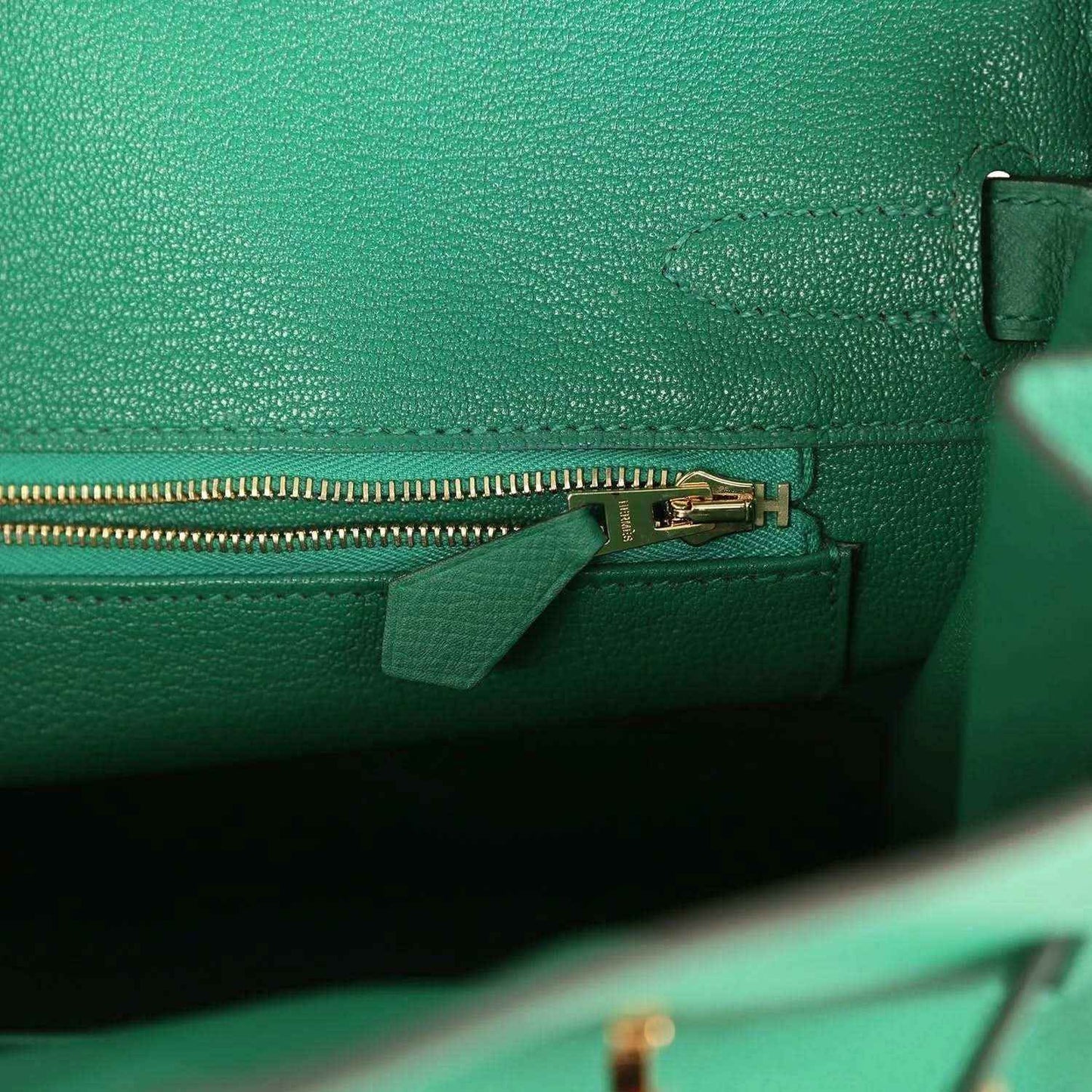 Green leather handbag with zipper track and small zipper pull hardware at side seam