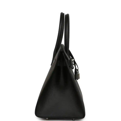 Black leather handbag, side view with top handles and hanging lock charm