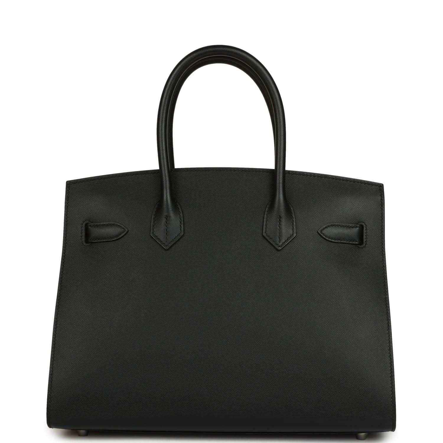 Black leather handbag with structured body, top handles, and front patch details