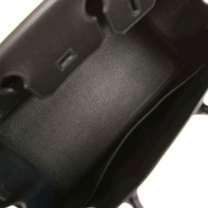 Black leather handbag close-up of textured panel and visible seam stitching