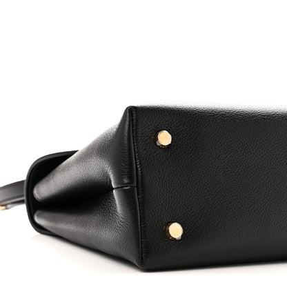 Black leather handbag side with two gold studs and curved corner seam
