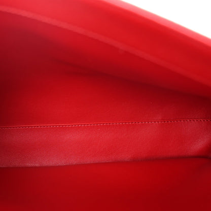 Close-up of red grained leather with contrast stitching along the bag edge