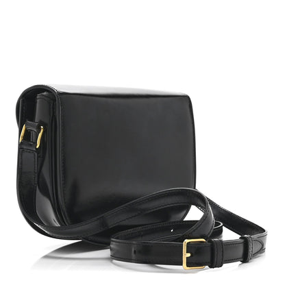 Black leather crossbody bag with flap closure, gold hardware accents, and adjustable strap