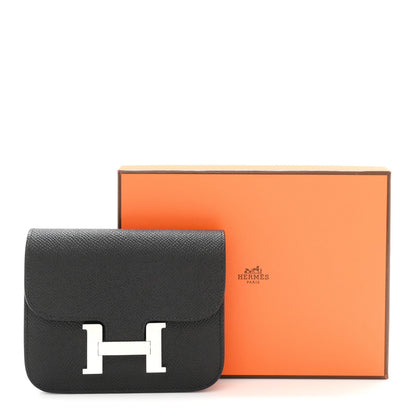 Black slim wallet with H clasp beside Hermes gift box.