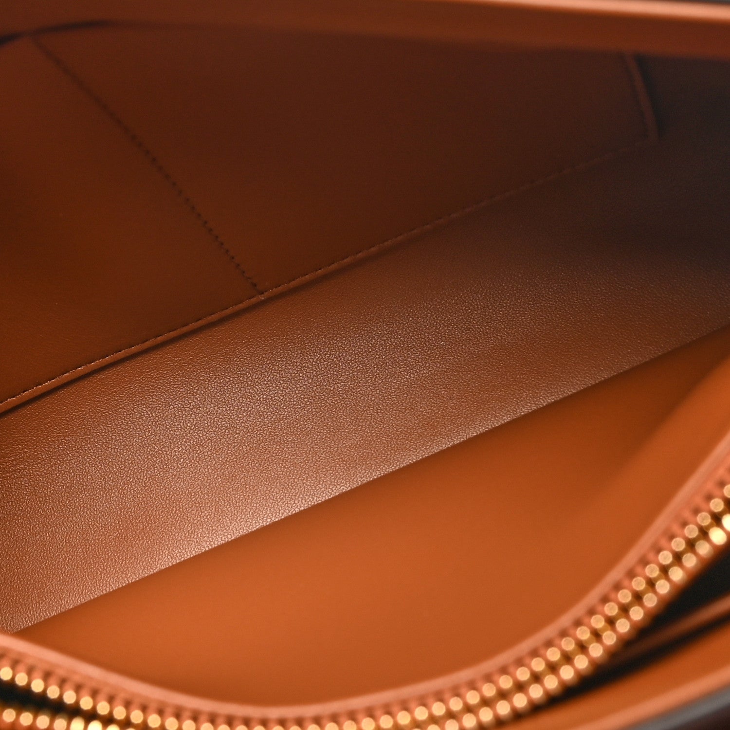 Tan leather handbag interior with smooth lining and gold-studded top edge trim