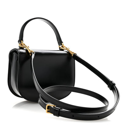 Black shiny mini crossbody bag with adjustable crossbody strap and gold-tone hardware