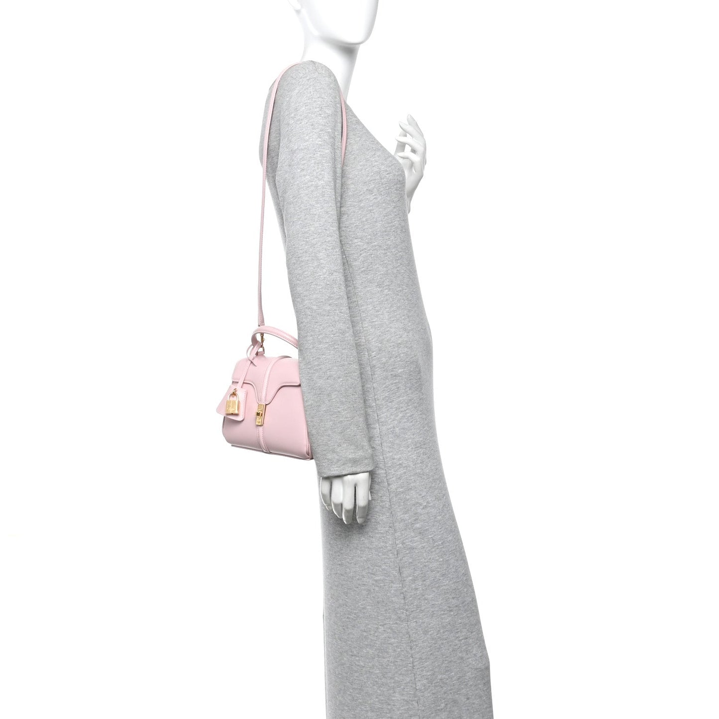 Pastel pink mini top-handle bag worn crossbody with thin strap and gold hardware