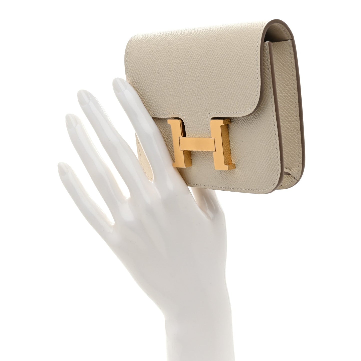 Slim wallet with flap and gold H clasp, side angle on light cream textured leather