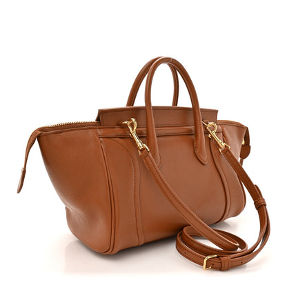 Tan leather small handbag with crossbody strap and gold-tone zippers and hardware.